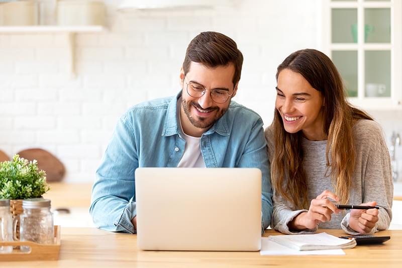Smiling woman taking notes in front of laptop